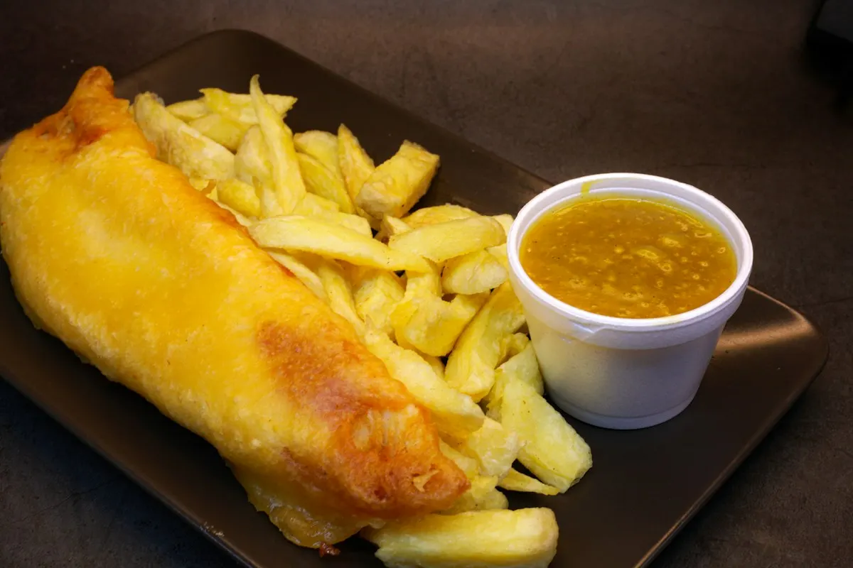 Battered fish and chips with a pot of curry sauce