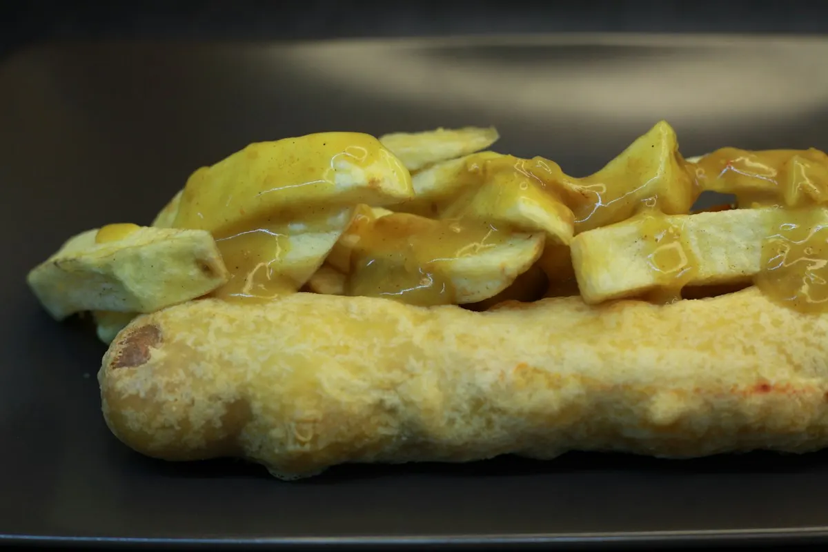 A sausage and chips covered with curry sauce